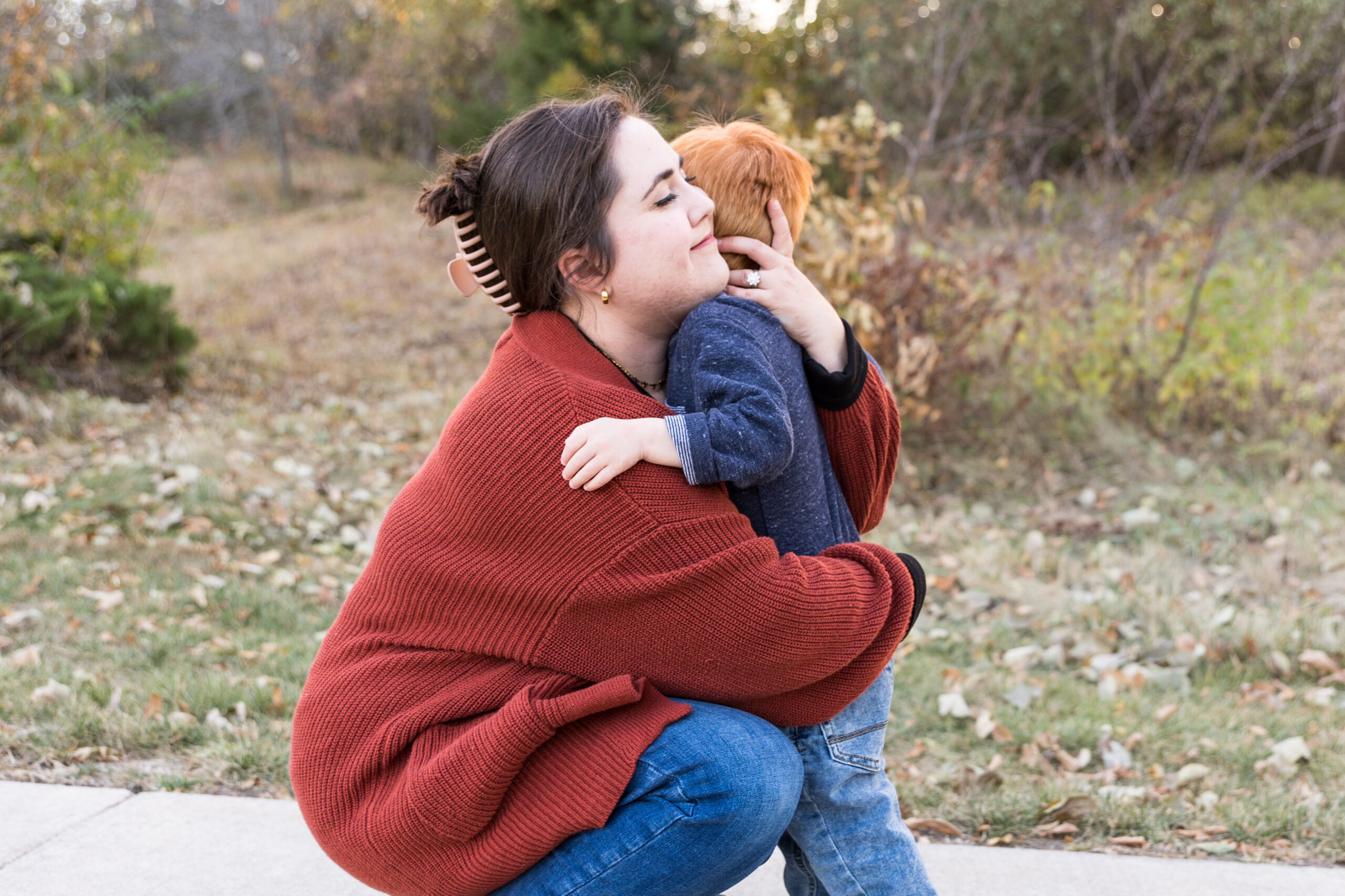 OCTA Marketing chair Lauren Ryan kneeling in an orange sweater hugging her child
