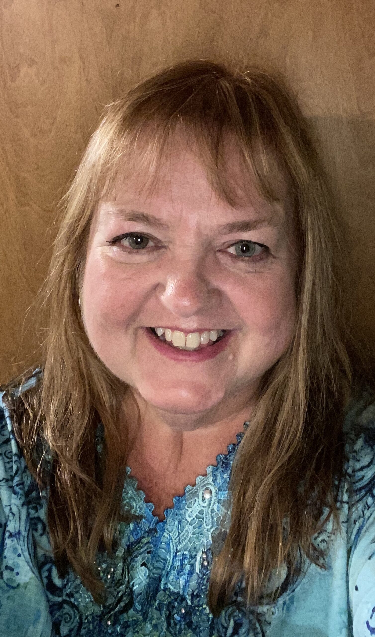 OCTA board president Shelly Stewart Banks, wearing a blue top, smiling, with hair past her shoulders